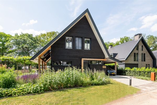 Vrijstaande houtskeletbouw woning zwart Zweeds Rabat in groene tuin
