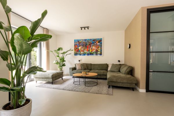 Woonkamer met gietvloer, arts behang en groene bank