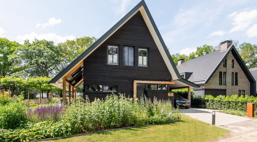 Vrijstaande houtskeletbouw woning zwart Zweeds Rabat in groene tuin