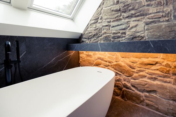 Badkamer met steenstrips achter vrijstaand bad
