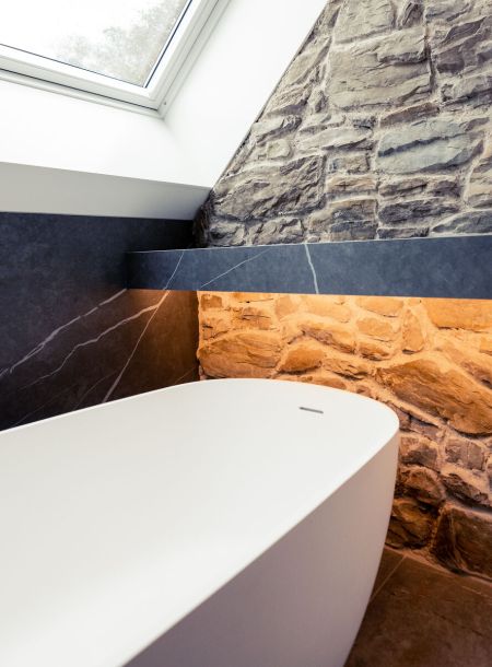 Badkamer met steenstrips achter vrijstaand bad